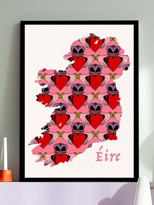 Framed artwork of a pink map of Ireland with hearts and 'Eire' text on a white wall.