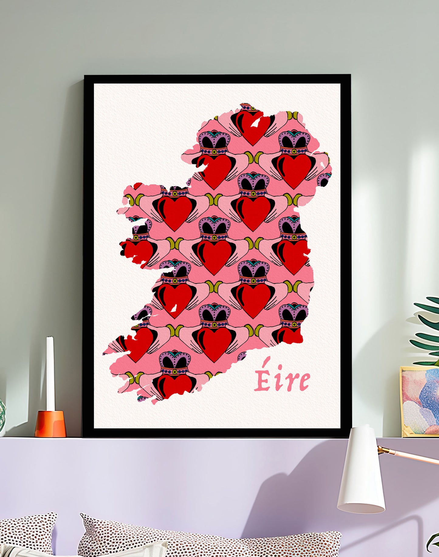 Framed artwork of a map of Ireland with  Claddagh hearts and 'Eire' text on a wall.